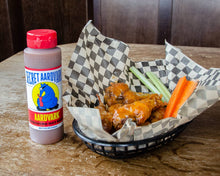 Load image into Gallery viewer, Bowl of wings with carrots and celery, accompanied by a bottle of Secret Aardvark sauce on a wooden table.