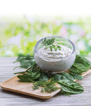 Load image into Gallery viewer, Bowl of dip with herbs on a wooden board with a blurred green background