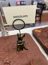 Load image into Gallery viewer, A chocolate bar display with a small metallic cat-shaped holder holding a card labeled 'CHOCOLATE' in a bakery or cafe setting.