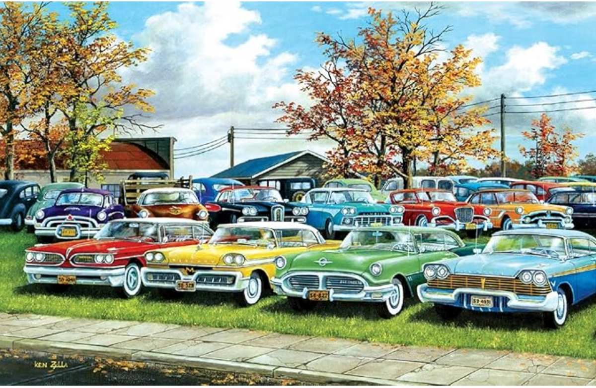 Collection of vintage cars parked in a lot with trees and a building in the background