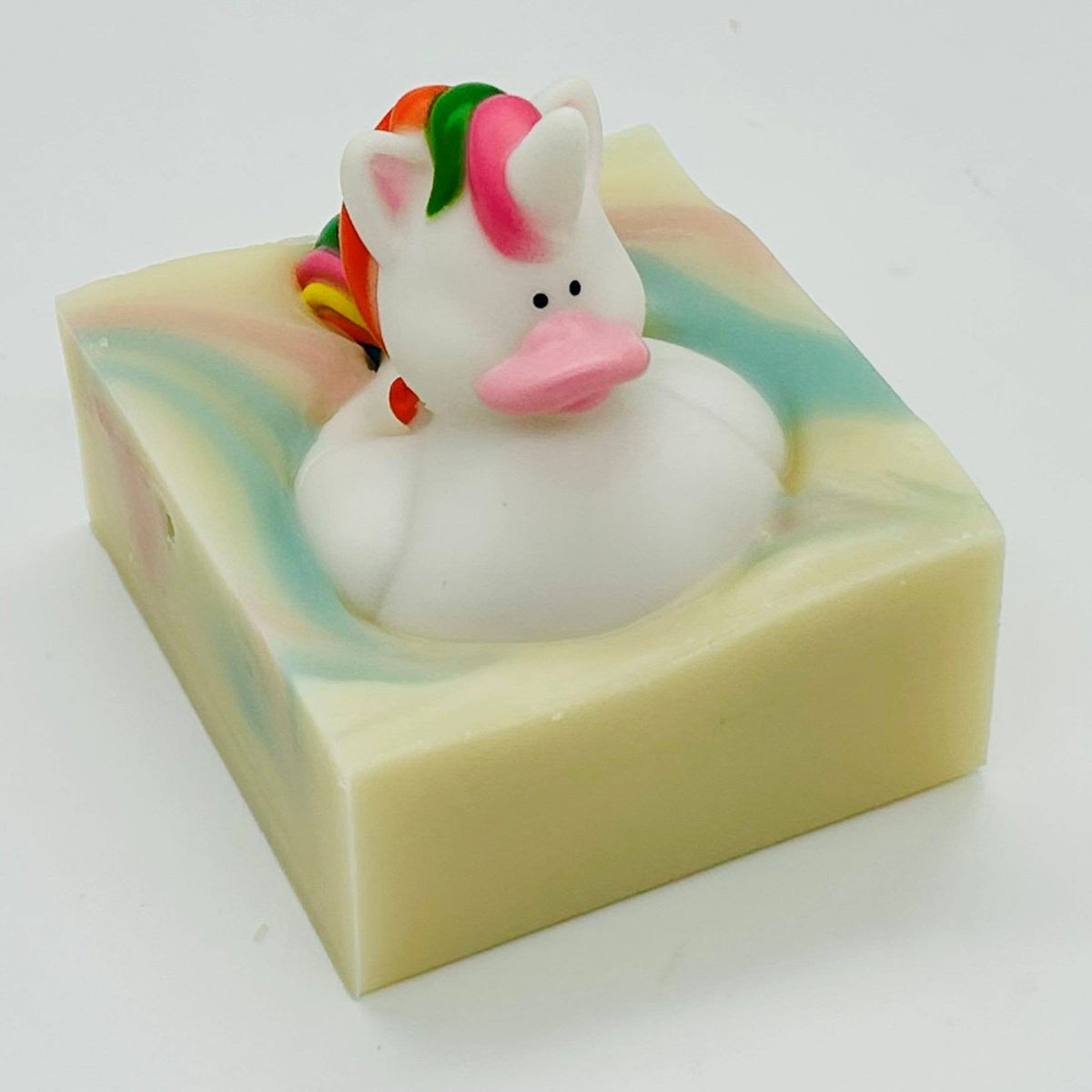 Unicorn-shaped rubber duck inside a colorful soap bar on a white background