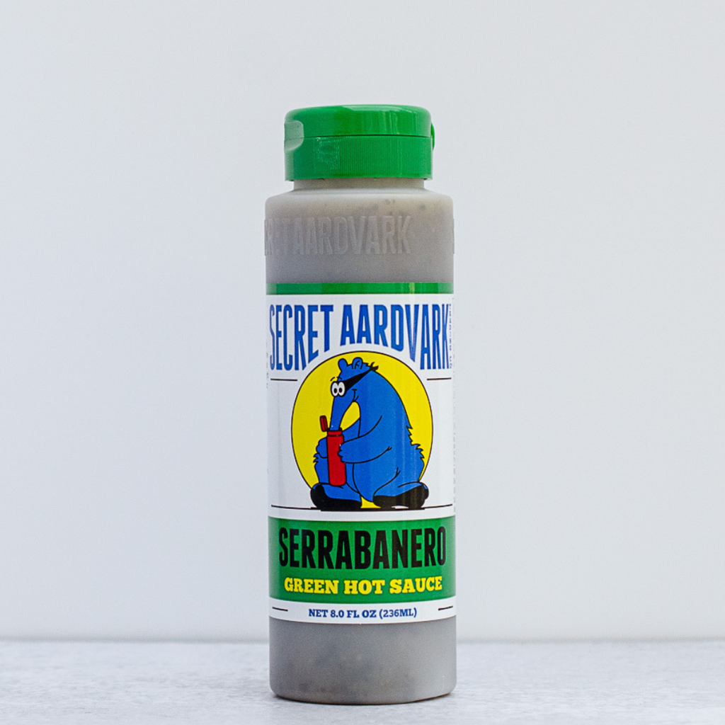 Secret Aardvark Serrabanero Green Hot Sauce bottle on a light gray background