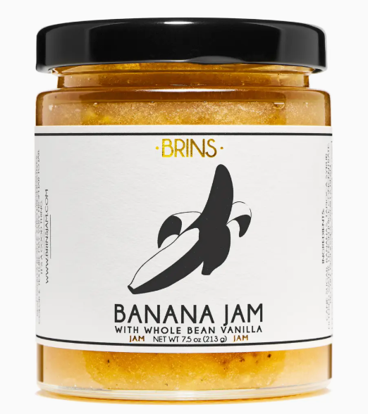 Jar of banana jam with a black lid and visible brand label on a white background