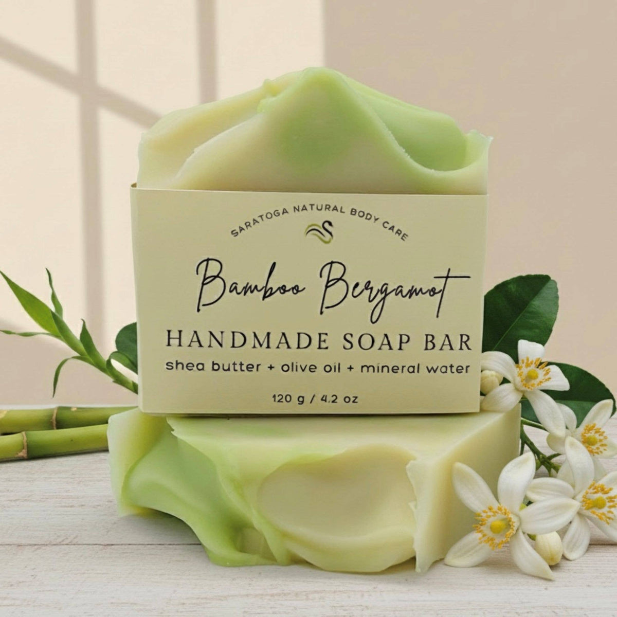 Handmade soap bar with a label on a light surface with bamboo and flowers.