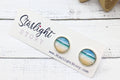 Earrings on a 'Starlight Story' branded card with a white wooden background