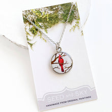 Load image into Gallery viewer, Necklace with a red bird pendant on a 'Seed and Sky' branded card.
