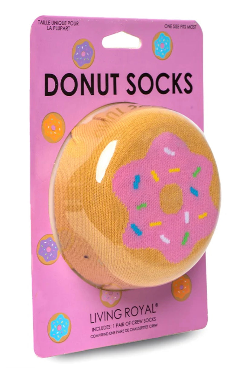 Packaged donut socks with pink icing and colorful sprinkles on a pink background, featuring the brand 'Living Royal'.