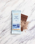 Malted milk chocolate bar and packaging on a marble surface