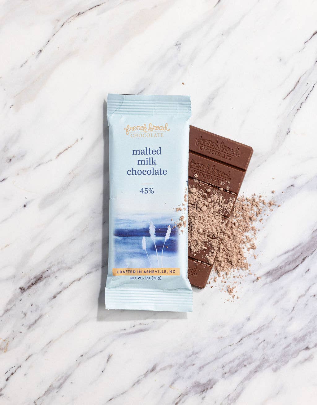 Malted milk chocolate bar and packaging on a marble surface