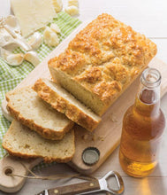 Load image into Gallery viewer, Loaf of bread with slices on a cutting board next to a bottle of beer.
