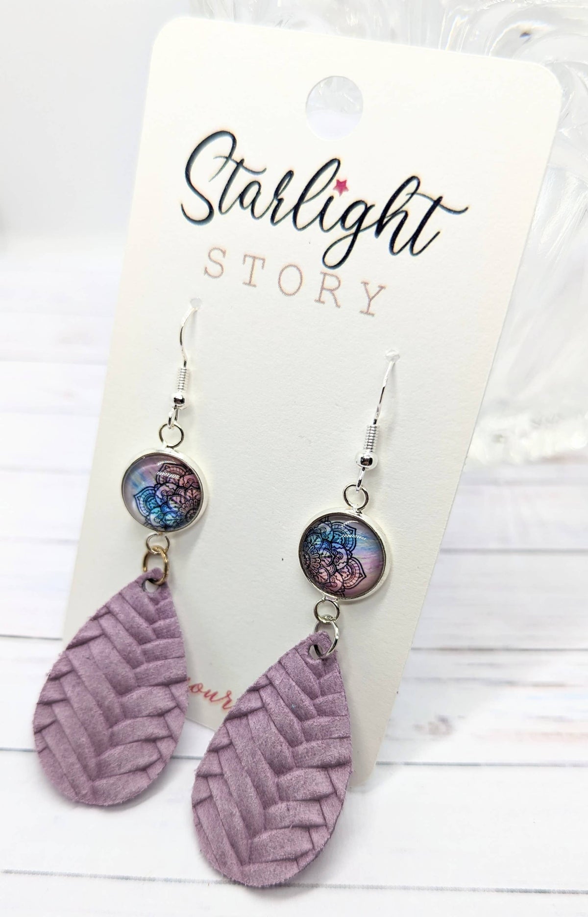 Pair of earrings with textured purple leaves and colorful beads on a 'Starlight Story' branded card.