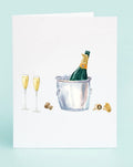 Greeting card with illustration of champagne bottle in ice bucket and flutes on light blue background