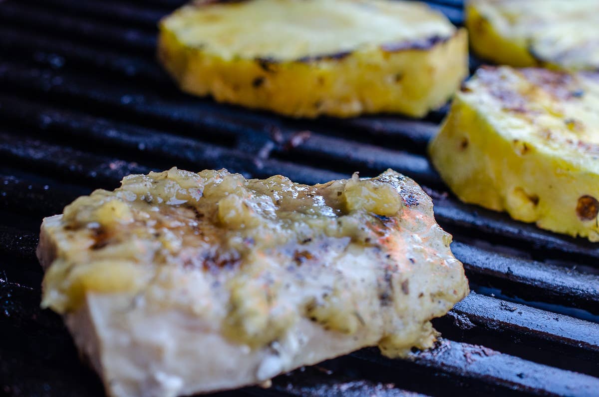 Grilled chicken breast and pineapple slices on a grill