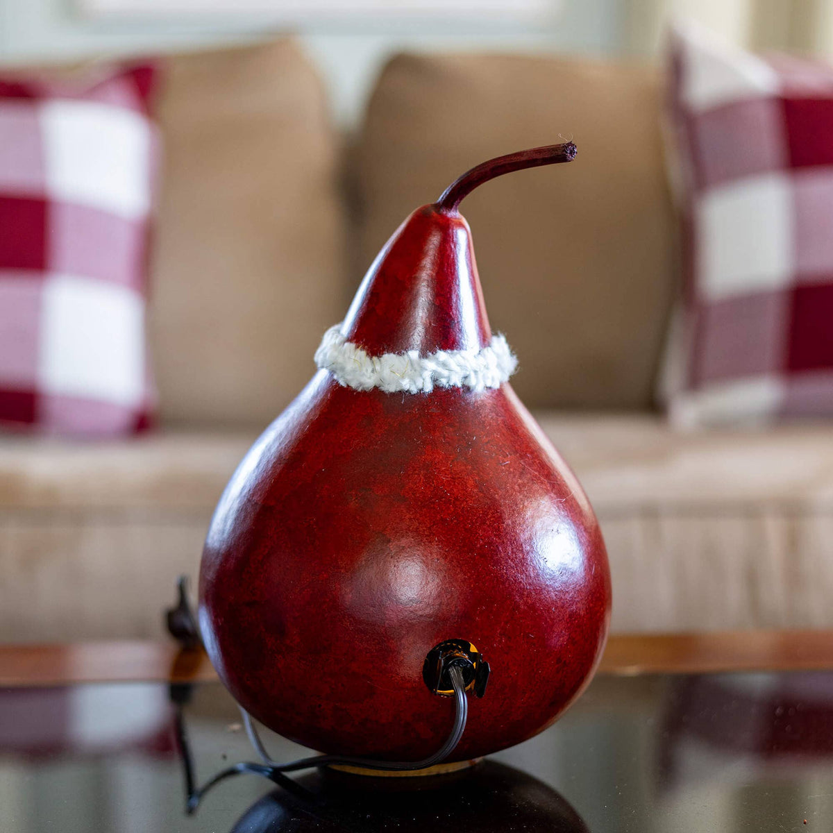 Decorative red gourd with a white base on a table with a blurred background