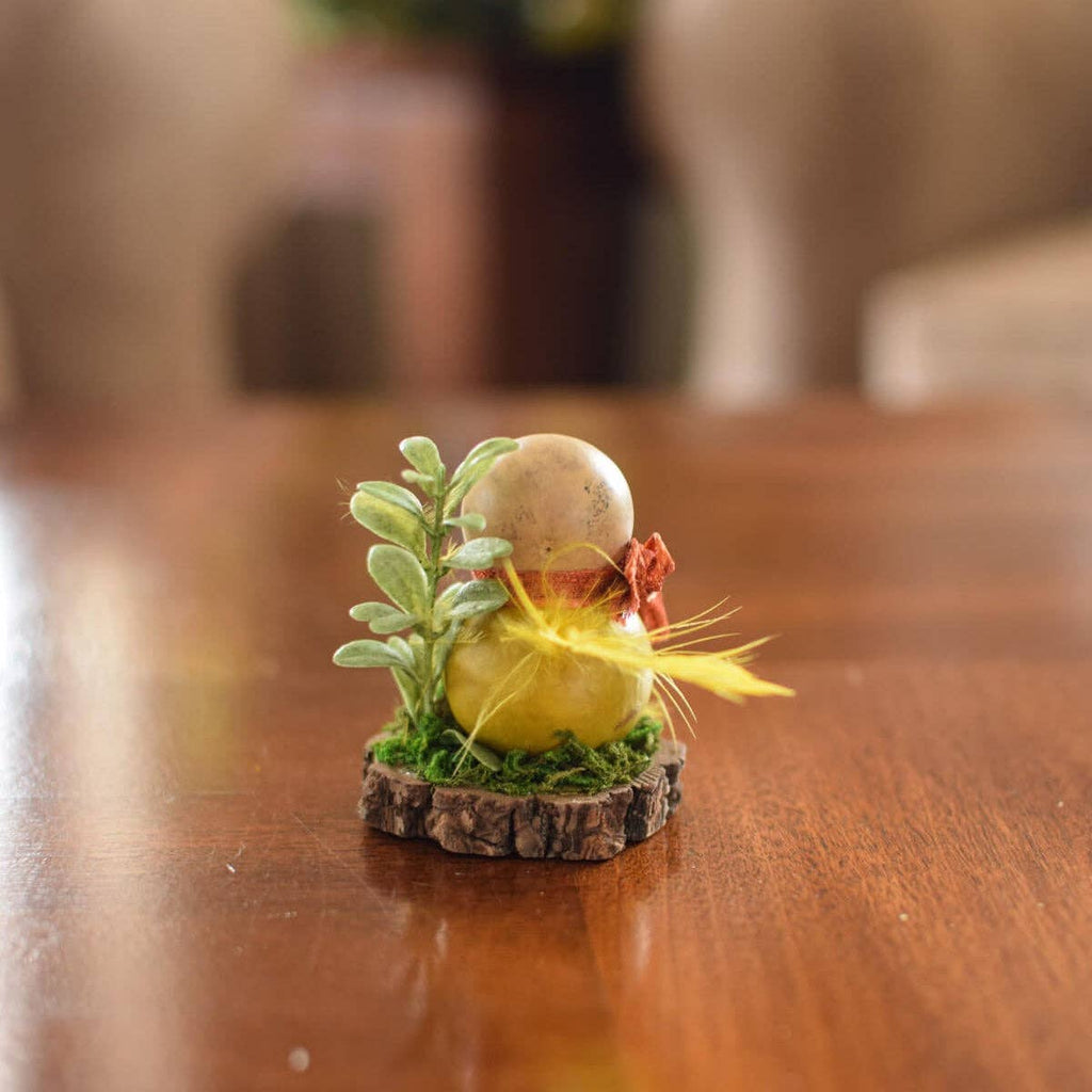 Small decorative figurine with a yellow ball and green leaves on a wooden surface