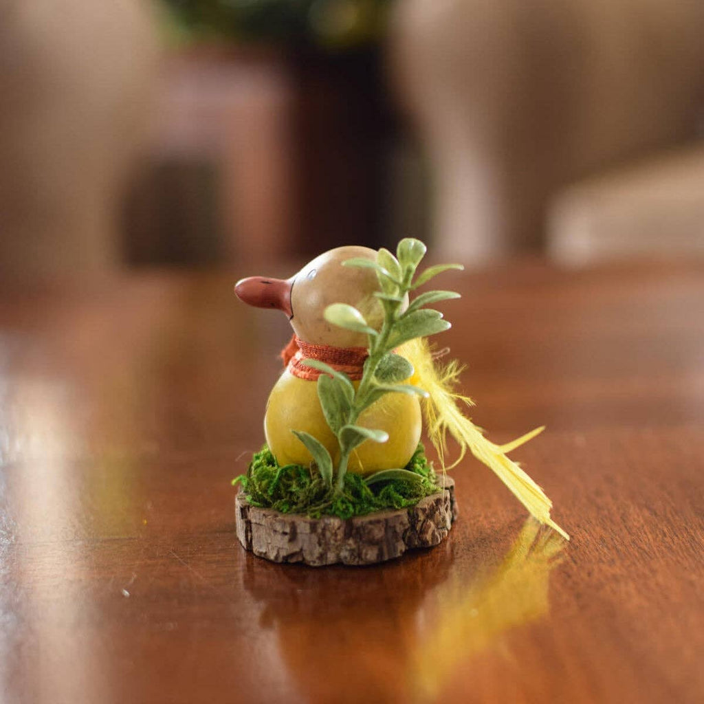 Small figurine of a character holding a plant on a wooden surface