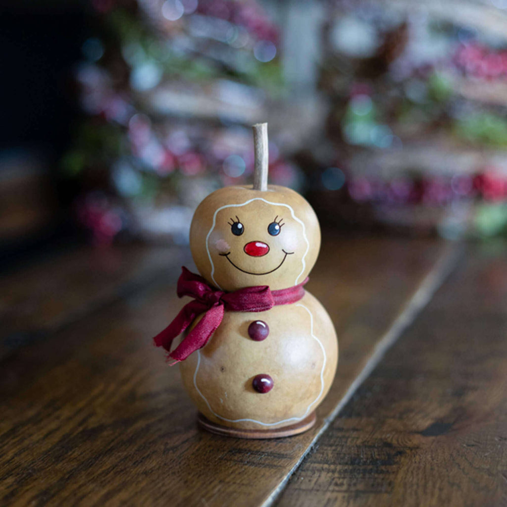 Decorative gingerbread man candle on a wooden surface with blurred festive background