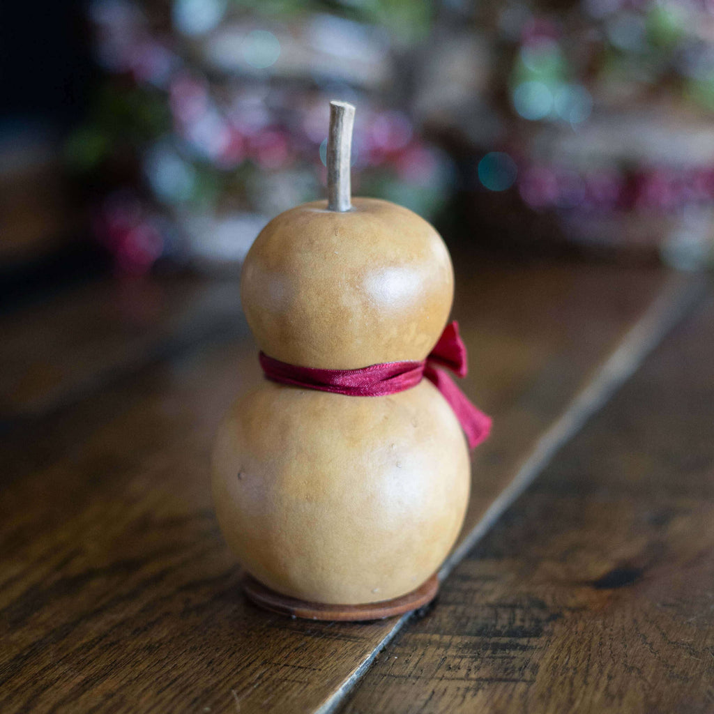Decorative gourd with a red ribbon on a wooden surface