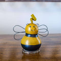 Decorative bee figure on a wooden surface with a blurred background