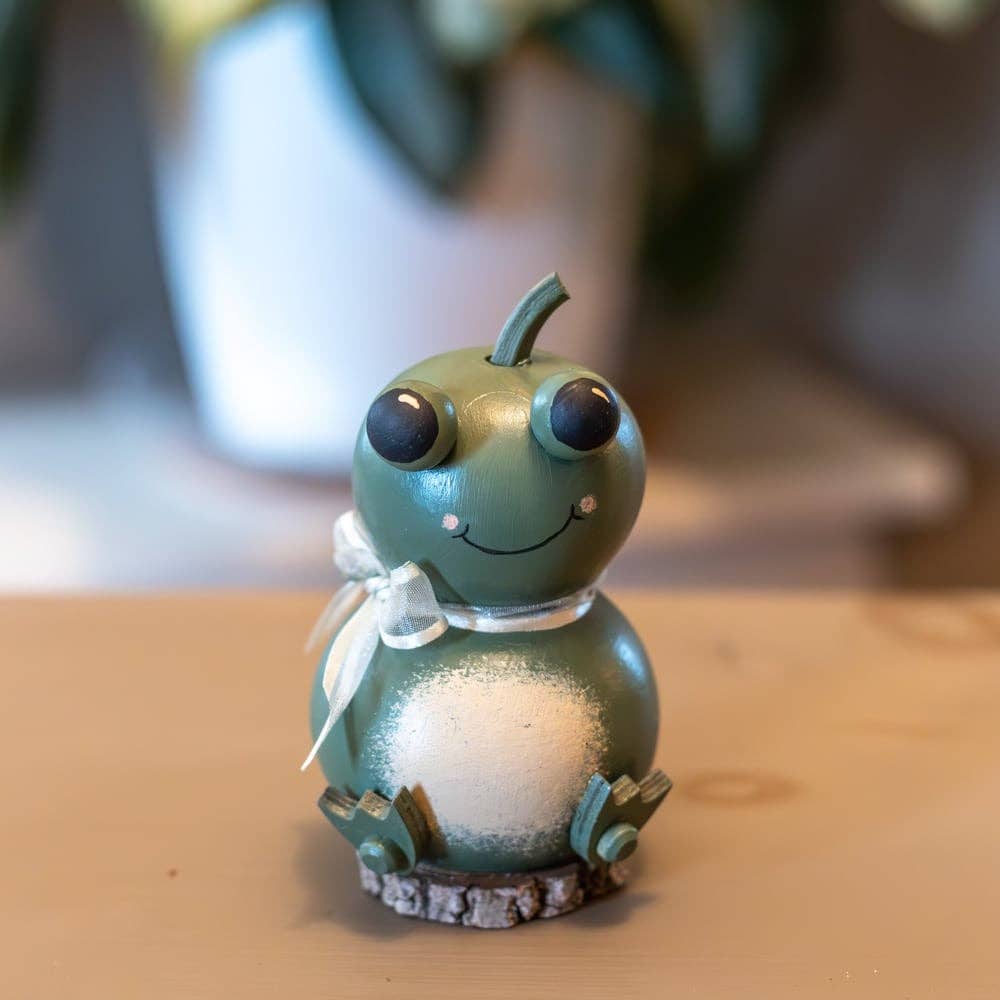 Green toy caterpillar with a white ribbon on a wooden surface