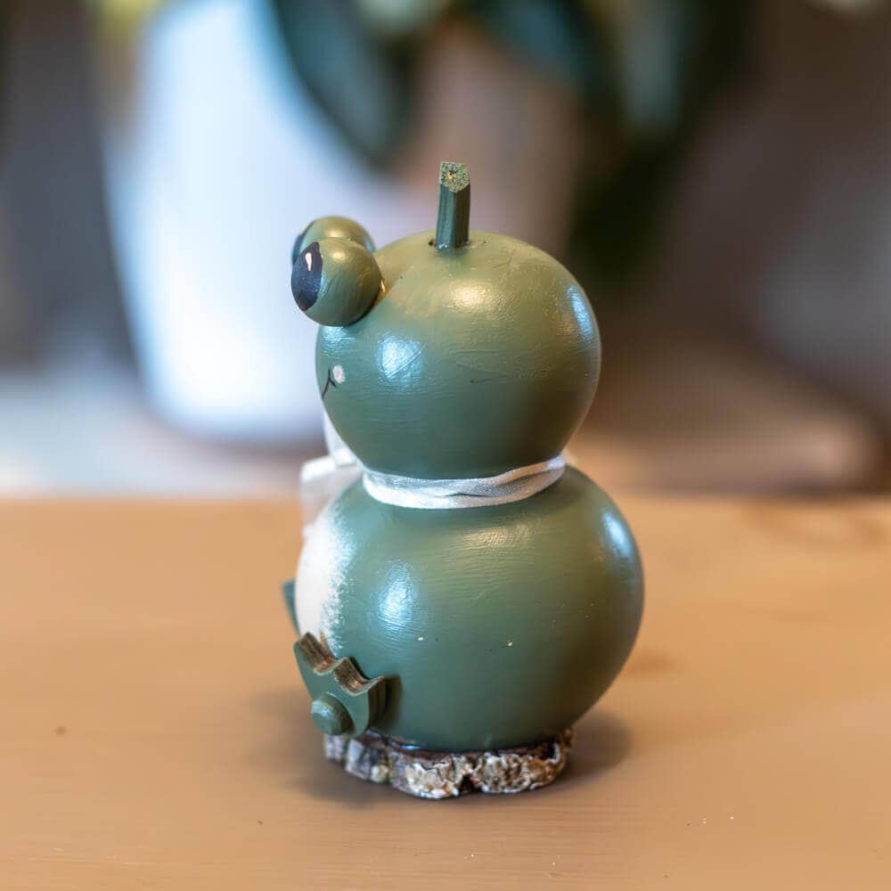 Green ceramic gourd with a face on a wooden surface