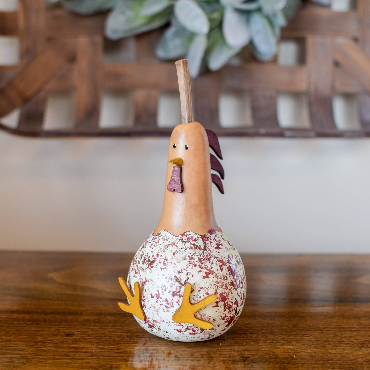 Decorative gourd shaped like a rooster on a wooden surface with a blurred background