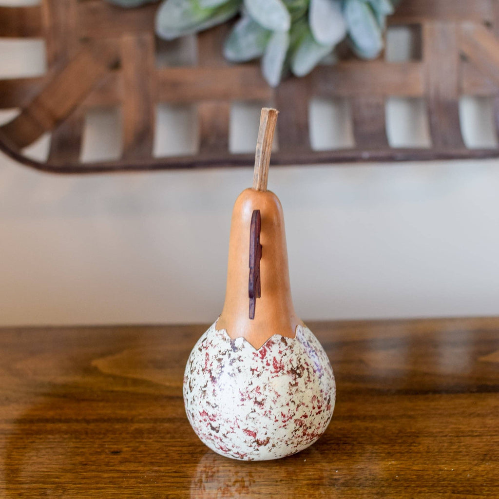 Decorative gourd with speckled pattern on a wooden surface