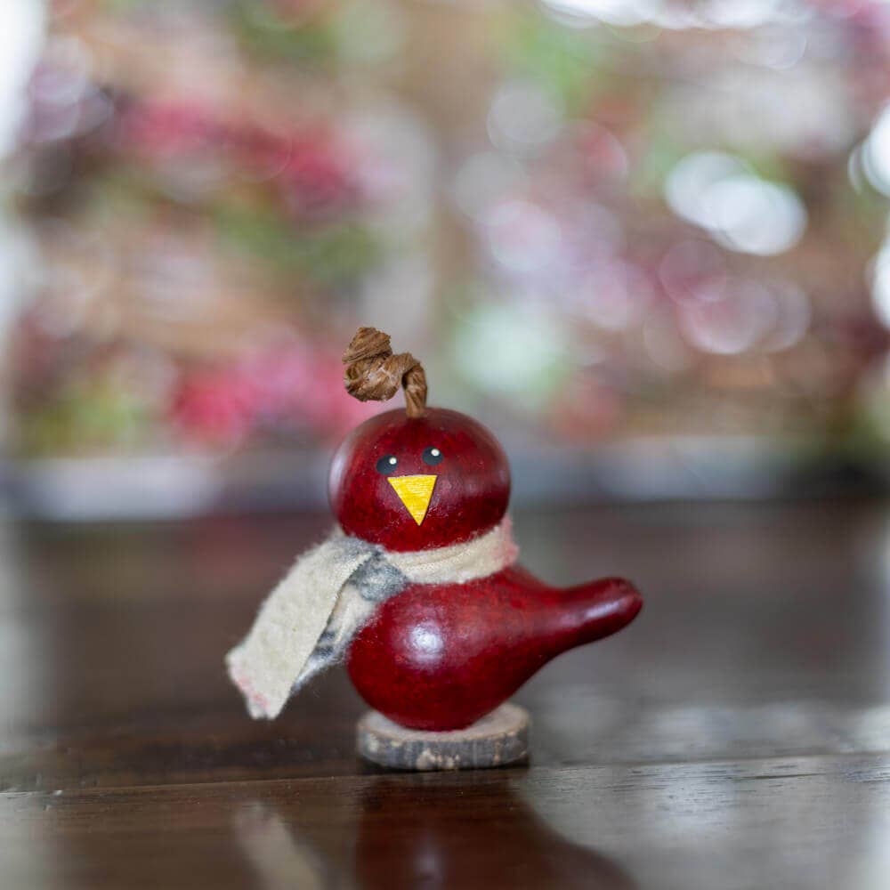 Red bird figurine with a yellow beak on a wooden surface
