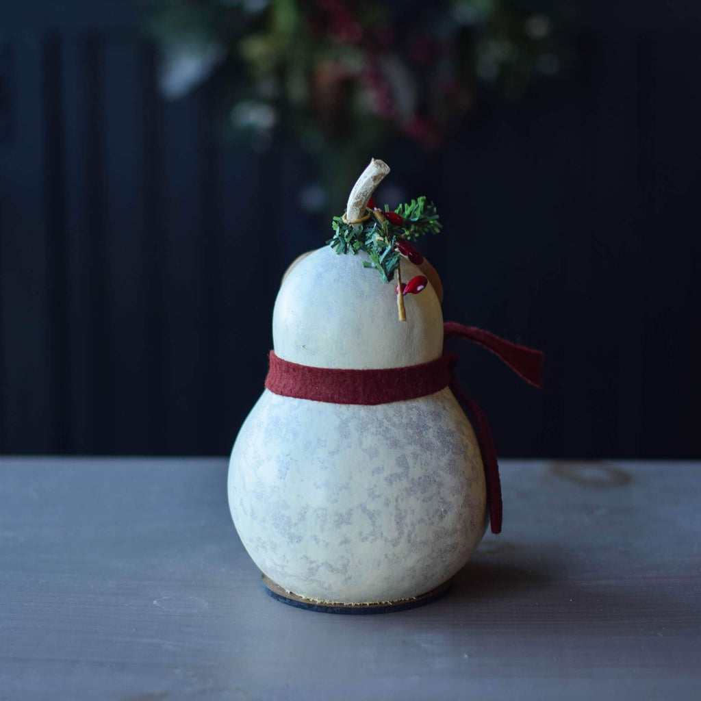 Decorative gourd with a red ribbon and small green branch on a dark background