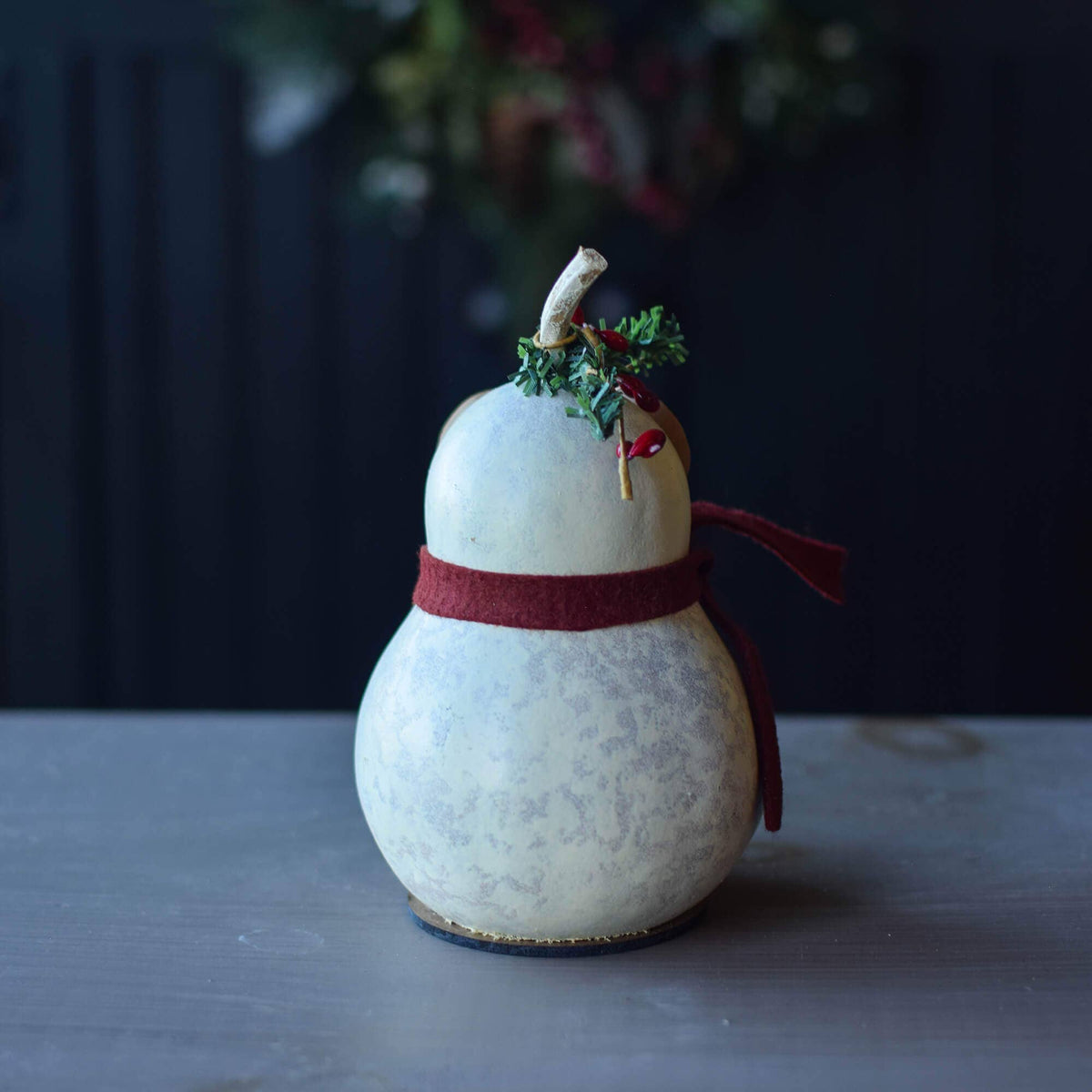 Decorative gourd with a red ribbon and small green branch on a dark background