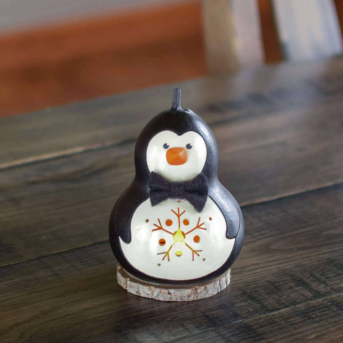 Penguin-shaped candle with a snowflake design on a wooden surface