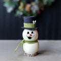 Decorative snowman figurine with a top hat and scarf on a neutral background