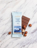 Hazel-nut milk chocolate bar with packaging on a marble surface