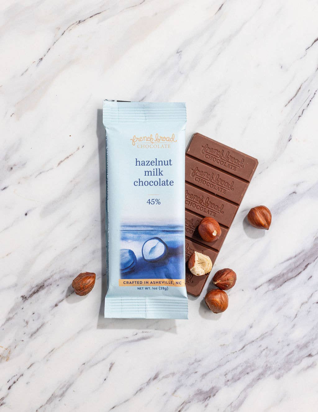 Hazel-nut milk chocolate bar with packaging on a marble surface