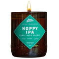 A lit Swag Brewery Hoppy IPA craft beer candle in a dark amber glass jar with a bright teal diamond-shaped label on the front.