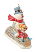 Decorative ornament of a snowman with a girl on his nose, sitting on a log.