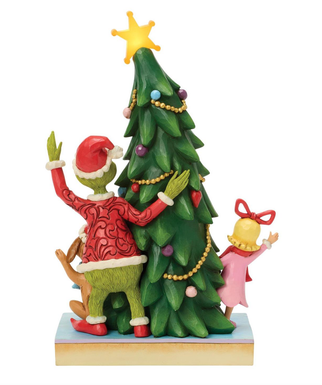 Decorative figurine of a character with a reindeer and a child next to a Christmas tree on a white background