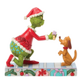 Statue of the Grinch and a dog in a festive setting