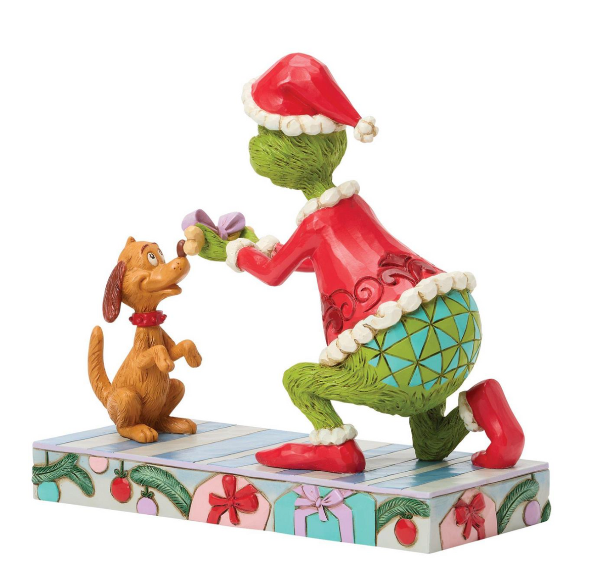 Figurine of a green character in a red Santa suit with a dog on a decorative base