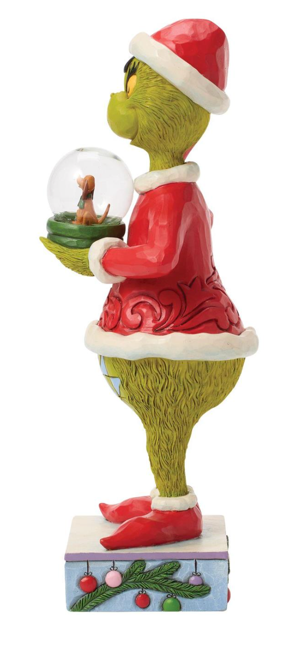 Figurine of a character in a Santa outfit holding a snow globe with a dog inside, on a white background.