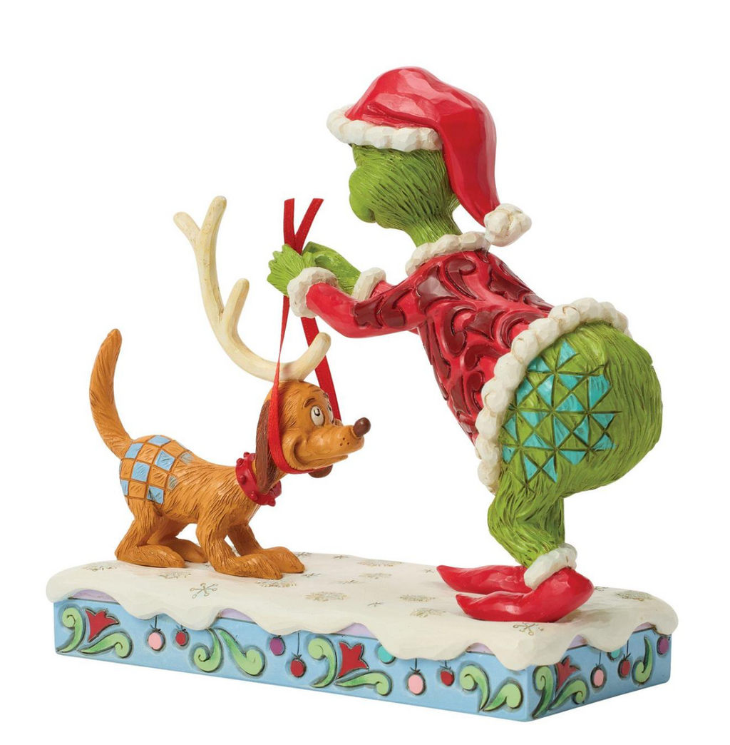 Decorative figurine of a character in a red hat and green body with a dog wearing antlers on a white background.