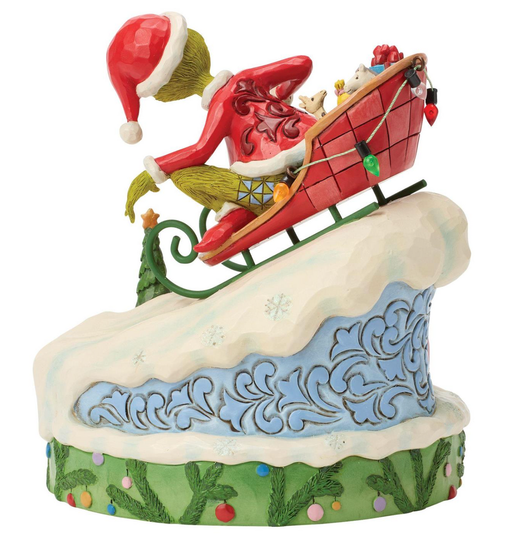Christmas-themed figurine of a character with a red hat and green scarf sliding down a snowy slope.