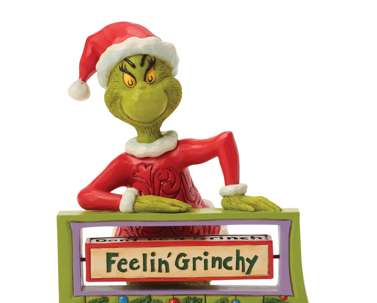 Grinch figurine with a sign saying 'Feelin' Grinchy' on a white background