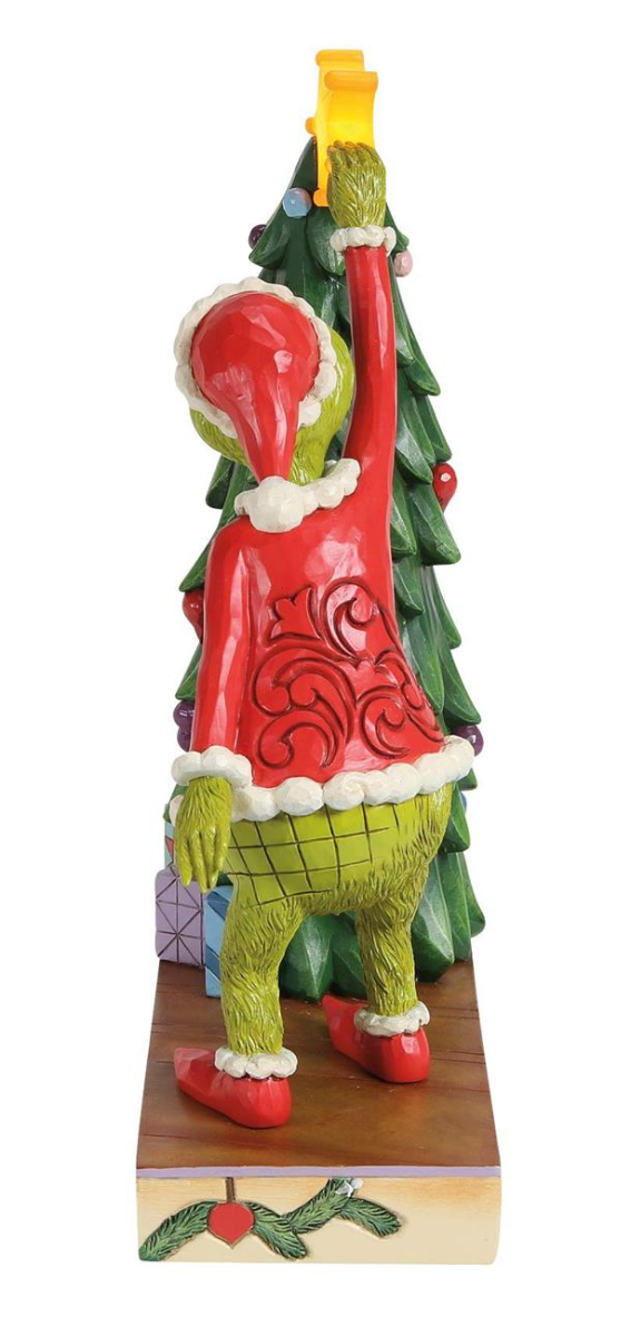 Christmas-themed figurine of a character in a red sweater and green pants with a tree on a white background.