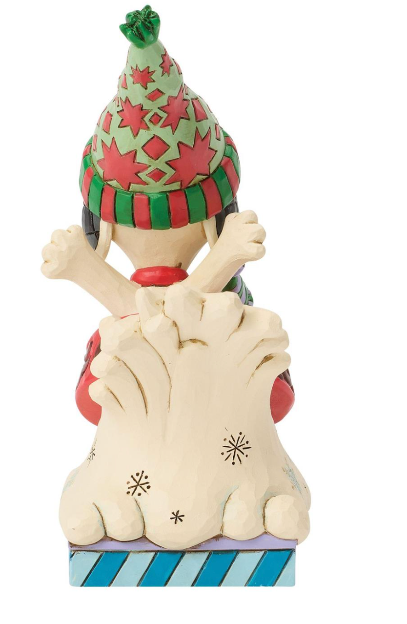 A Christmas gnome figurine peeking out from behind a snowdrift, wearing a green and red patterned hat and scarf, with a blue and white striped base.