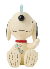 Load image into Gallery viewer, A decorative figurine of Snoopy sitting down, made of cream-colored material with black line details, a red collar, and light blue accents on his ear and chest, with a small translucent blue hanging loop at the top.
