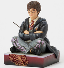 Load image into Gallery viewer, Figurine of a Harry Potter in a gray robe with a wand, sitting on a decorative base.Artist Jim Shore.

