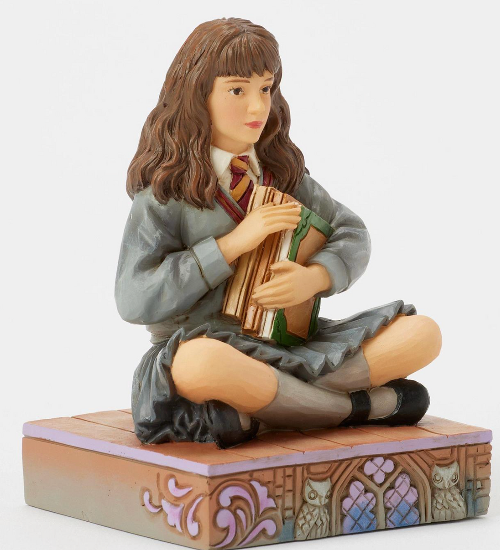 Figurine of Hermione in a school uniform holding books on a decorative base with owls. Artist Jim Shore.