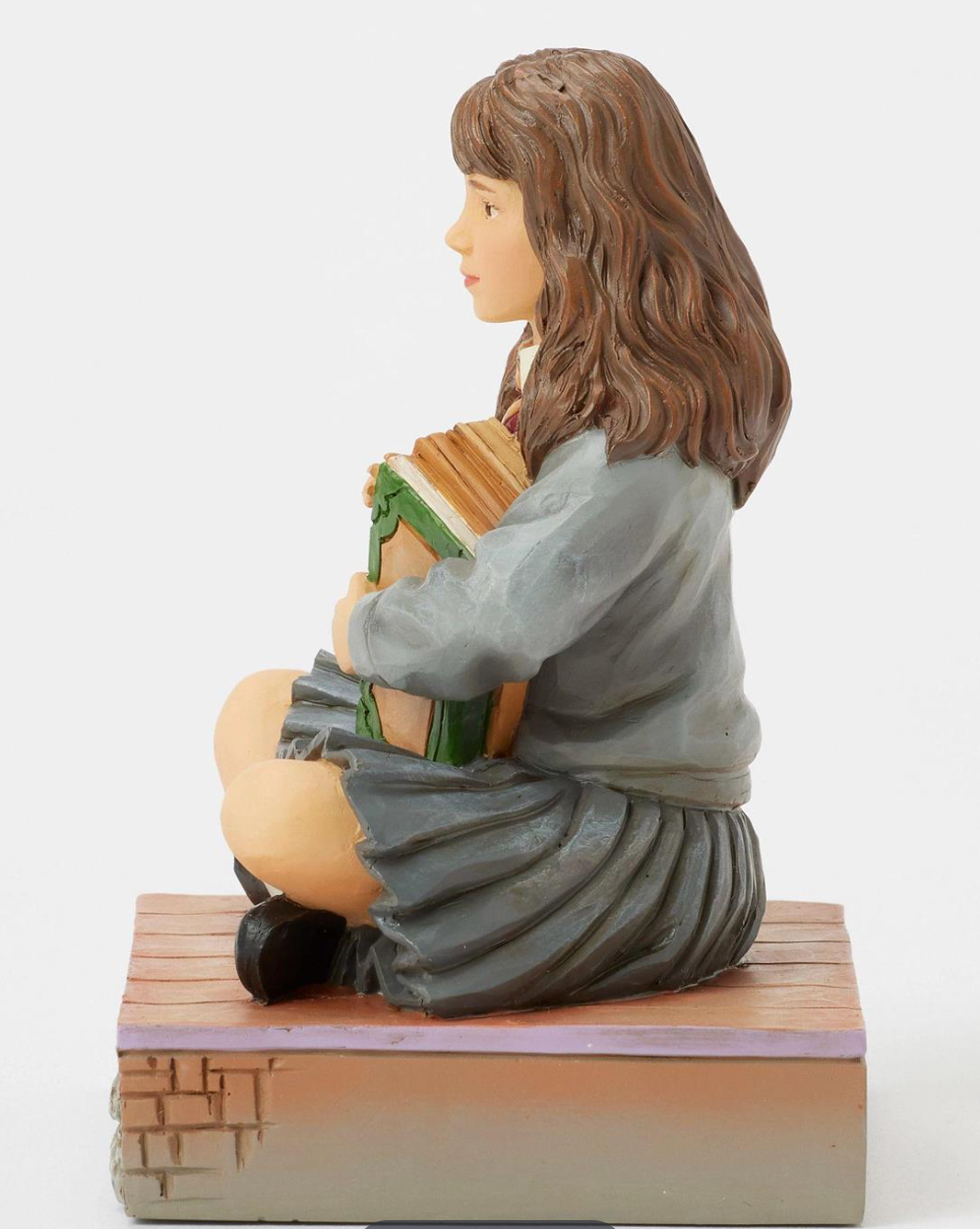 Figurine of Hermione in a school uniform holding books on a decorative base with owls. Artist Jim Shore.