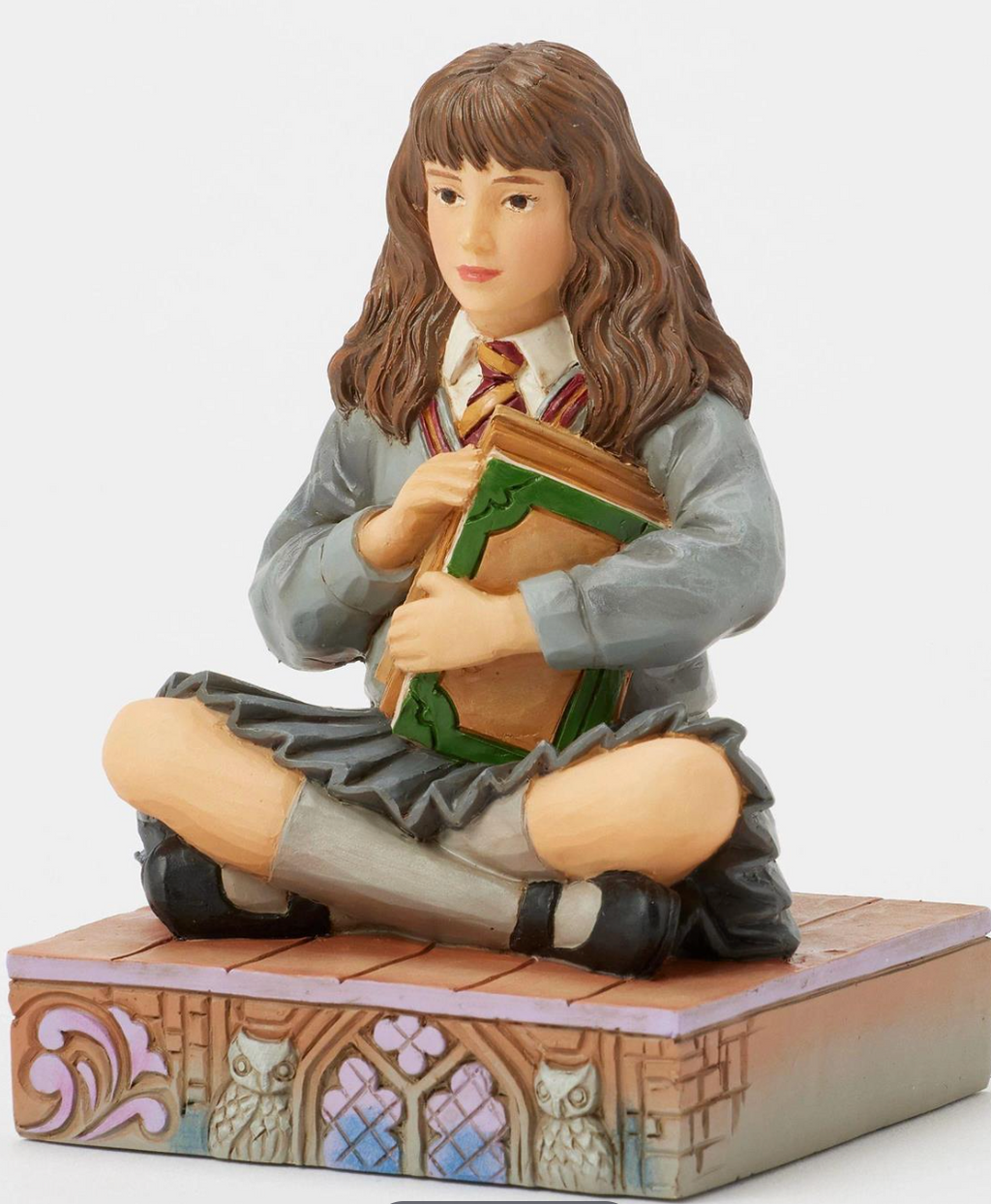 Figurine of Hermione in a school uniform holding books on a decorative base with owls. Artist Jim Shore.